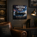Decorative wall art of USS Abraham Lincoln on a dark wall with a brown leather chair and books in the foreground.