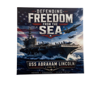 Decorative banner with USS Abraham Lincoln aircraft carrier and text 'Defending Freedom from the Sea'.