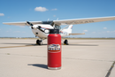Cessna vintage badge airplane sticker on a red water bottle on the airport ramp with a Cessna 172 in the background