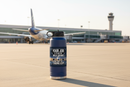 Your Job as a First Officer sticker on a navy blue water bottle on the airport ramp with an Airbus A320 jet in the background
