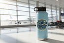 Cabin Crew Global Wings Est. 1945 flight attendant sticker on a light blue water bottle in a modern airport terminal with a commercial jet at the gate outside