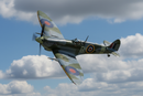 Supermarine Spitfire WWII fighter aircraft flying against blue sky with clouds